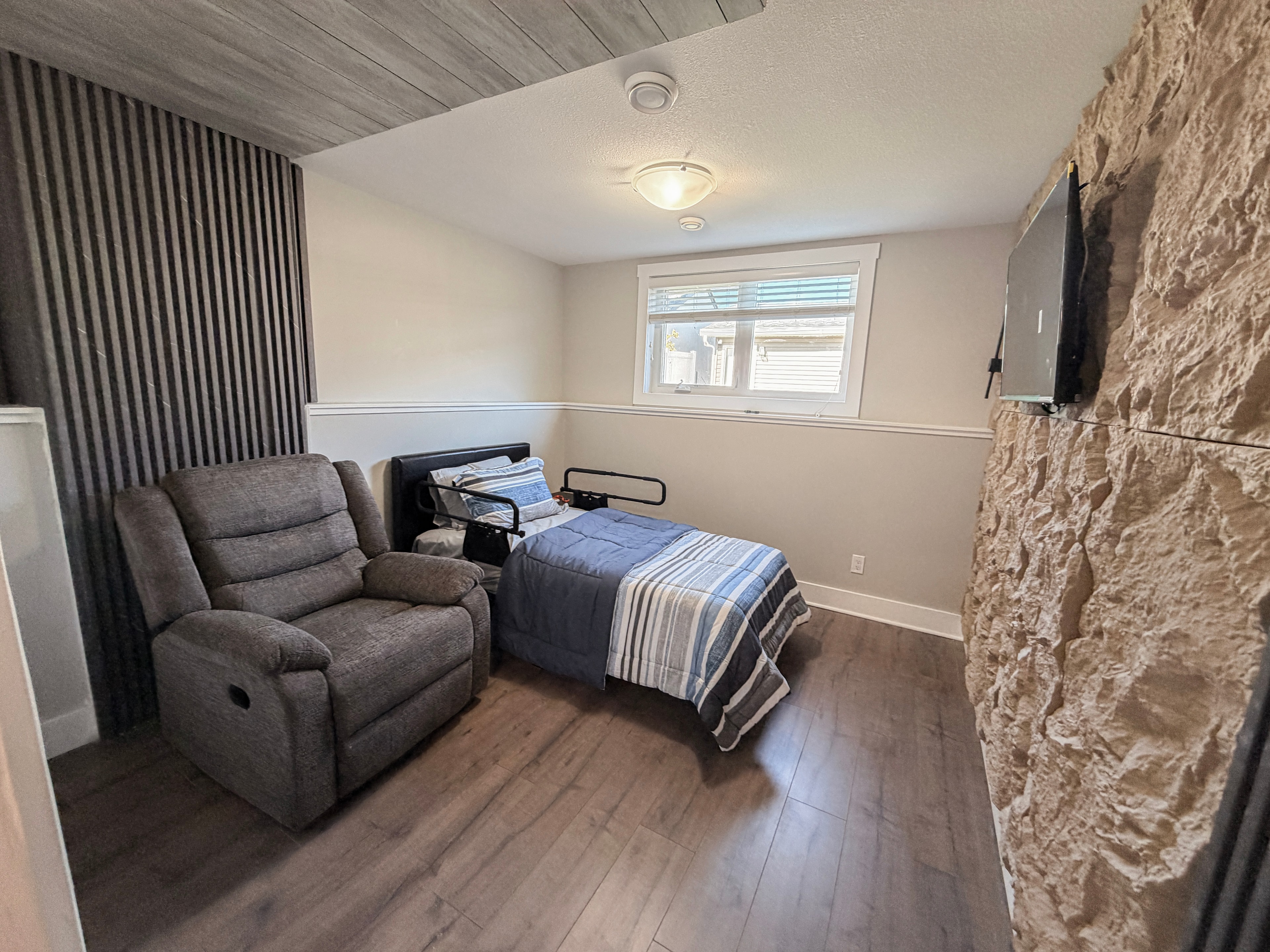 Bedroom with recliner and stone accent wall